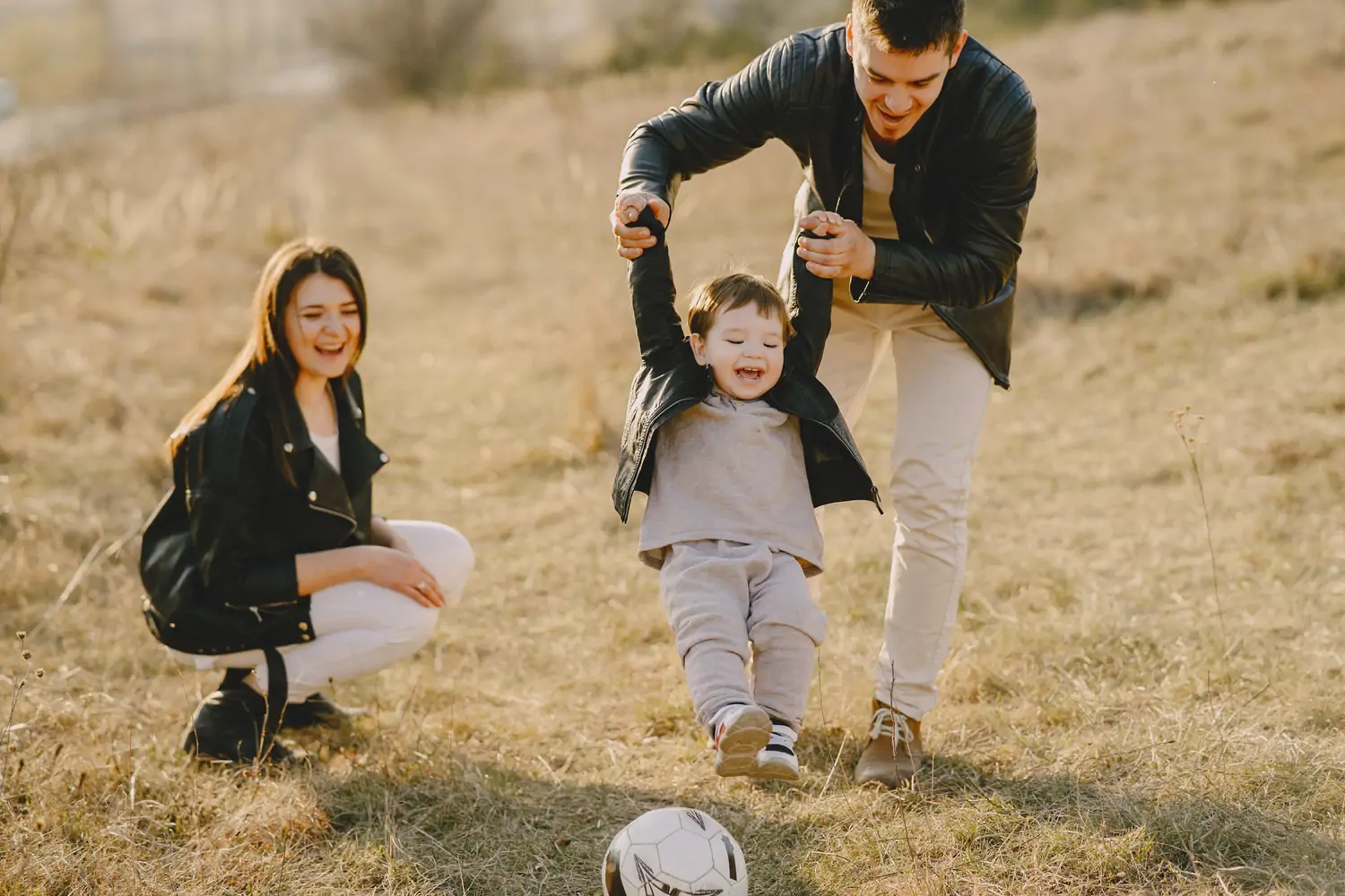A mom and dad helping their son walk